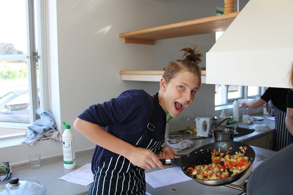 Glad kokkeelev i Gastronomi linjefaget står med pande og smiler