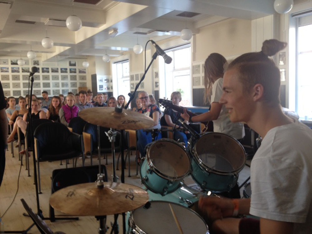 Dagligdagen med en elev der spiller på trommer, med alle elever og lærere siddende foran sig